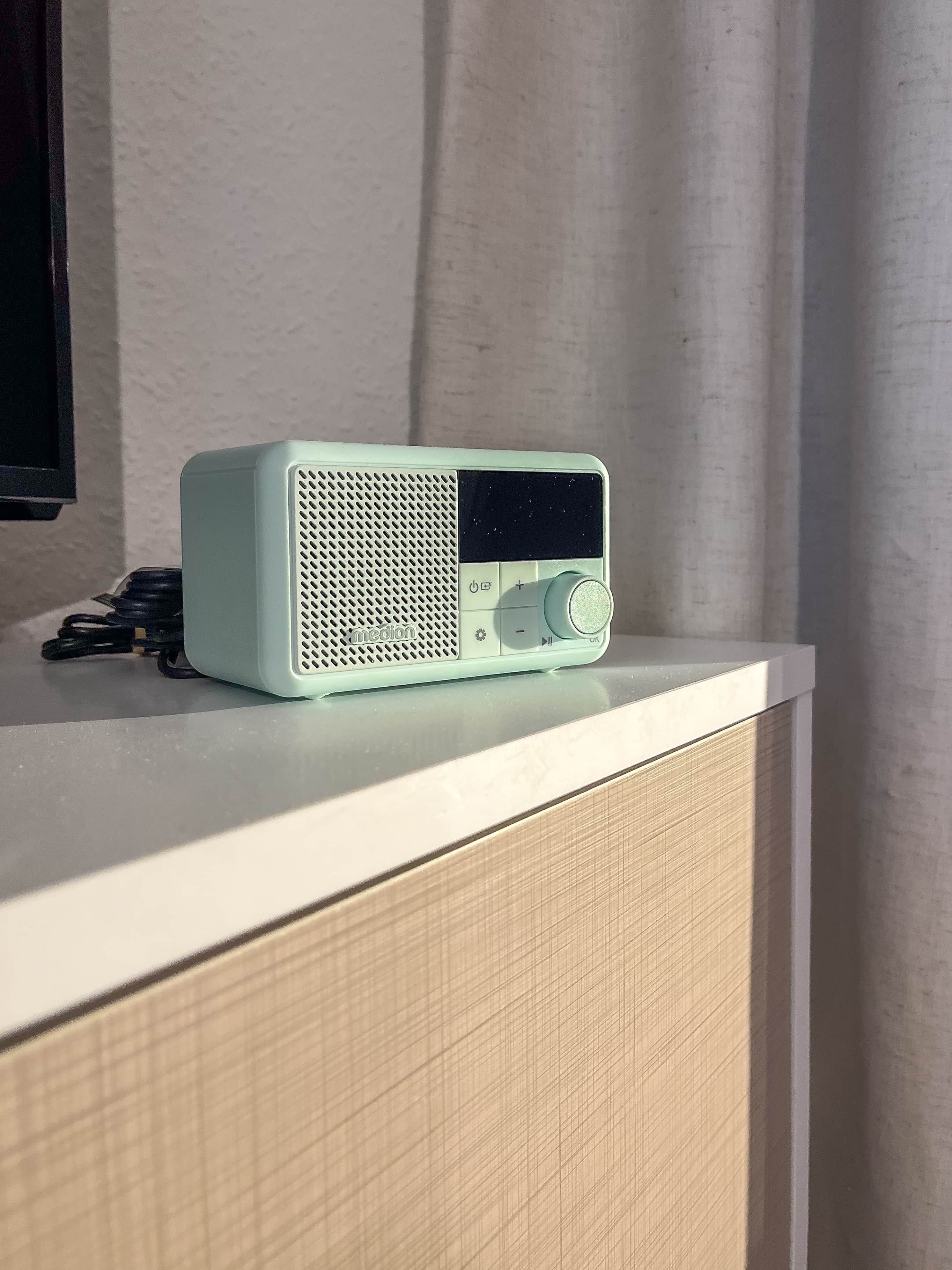 A light green portable radio with a speaker and control buttons on a white surface.