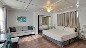 Una camera da letto con un letto, un divano, una cassettiera e una ventola a soffitto.