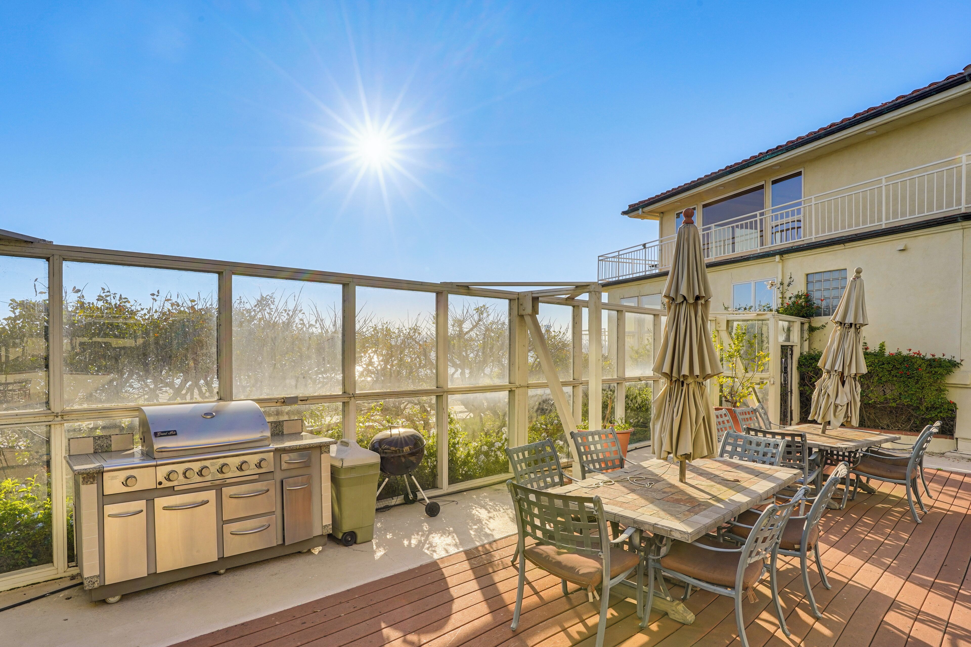 A covered patio with a grill, outdoor furniture, and a view of the house.