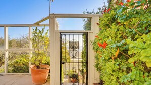 A gated entrance with a potted plant and a view of the surrounding greenery. - Beachfront Living in Long Beach: 2,500 Sq Ft Condo (Long Beach)