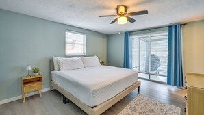 Ein Schlafzimmer mit einem Bett, einem Nachttisch, einem Deckenventilator und einem Fenster mit Jalousien.