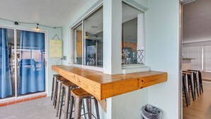 Eine Küche mit einer Holztresen, Hockern und einem Mülleimer.