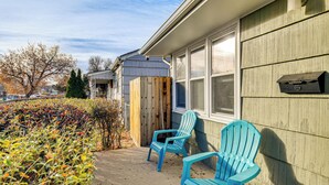 Een huis met een veranda, twee blauwe Adirondack-stoelen en een brievenbus op de muur.