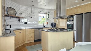Een moderne keuken met een witte tegelachtergrond, houten kasten en roestvrijstalen apparatuur, inclusief een centraal eiland.