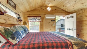 Camera accogliente di una baita con un letto grande, una finestra con tende, una porta e un velux.