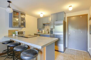 A kitchen with a central island, bar stools, stainless steel appliances, and a cabinet with glass doors.