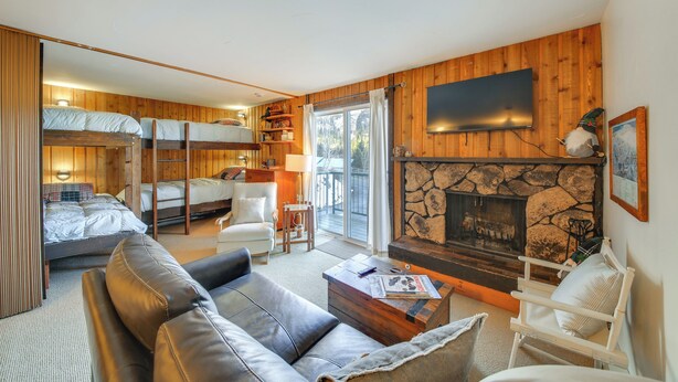 A cozy cabin interior with a living room, a fireplace, a television, and a bunk bed area. - Walk to Chair Lift: Mtn-view Schweitzer Studio! (Sandpoint)