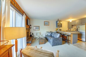 A living room with a sofa, a coffee table, and a TV. There is a kitchen area with a refrigerator and a microwave. - Walk to Chair Lift: Mtn-view Schweitzer Studio! (Sandpoint)