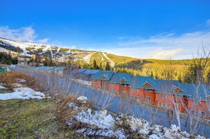 A row of red buildings with blue roofs, surrounded by snow-covered ground and trees.