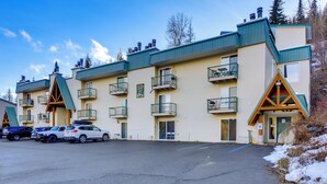 A multi-story hotel with balconies, a parking lot, and a snow-covered ground. - Walk to Chair Lift: Mtn-view Schweitzer Studio! (Sandpoint)