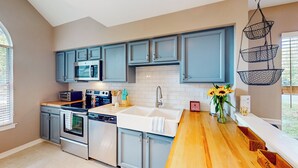 A modern kitchen with blue cabinets, a wooden countertop, stainless steel appliances, and a hanging basket. - 3BR Dog-friendly Retreat w/ Fireplace & Patio (Annapolis)
