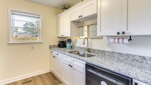 A kitchen with white cabinets, a granite countertop, a dishwasher, and a window with blinds. - Quiet & Modern Family Home in Spring Lake (Spring Lake)