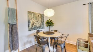 A dining area with a round table, four chairs, a hanging light fixture, a painting on the wall, and a plant. - Quiet & Modern Family Home in Spring Lake (Spring Lake)