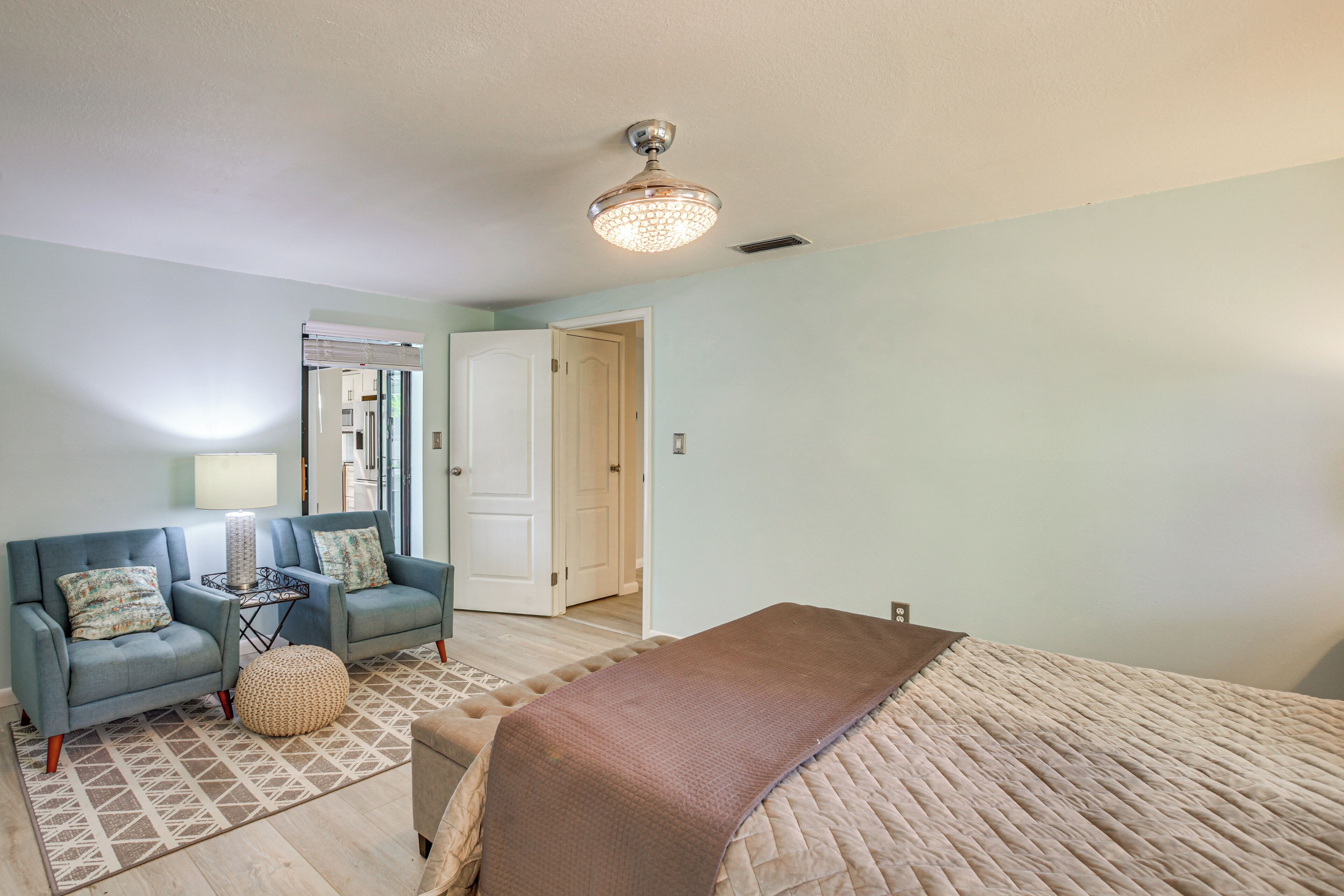 A bedroom with a bed, a blue sofa, a small table, and a lamp.