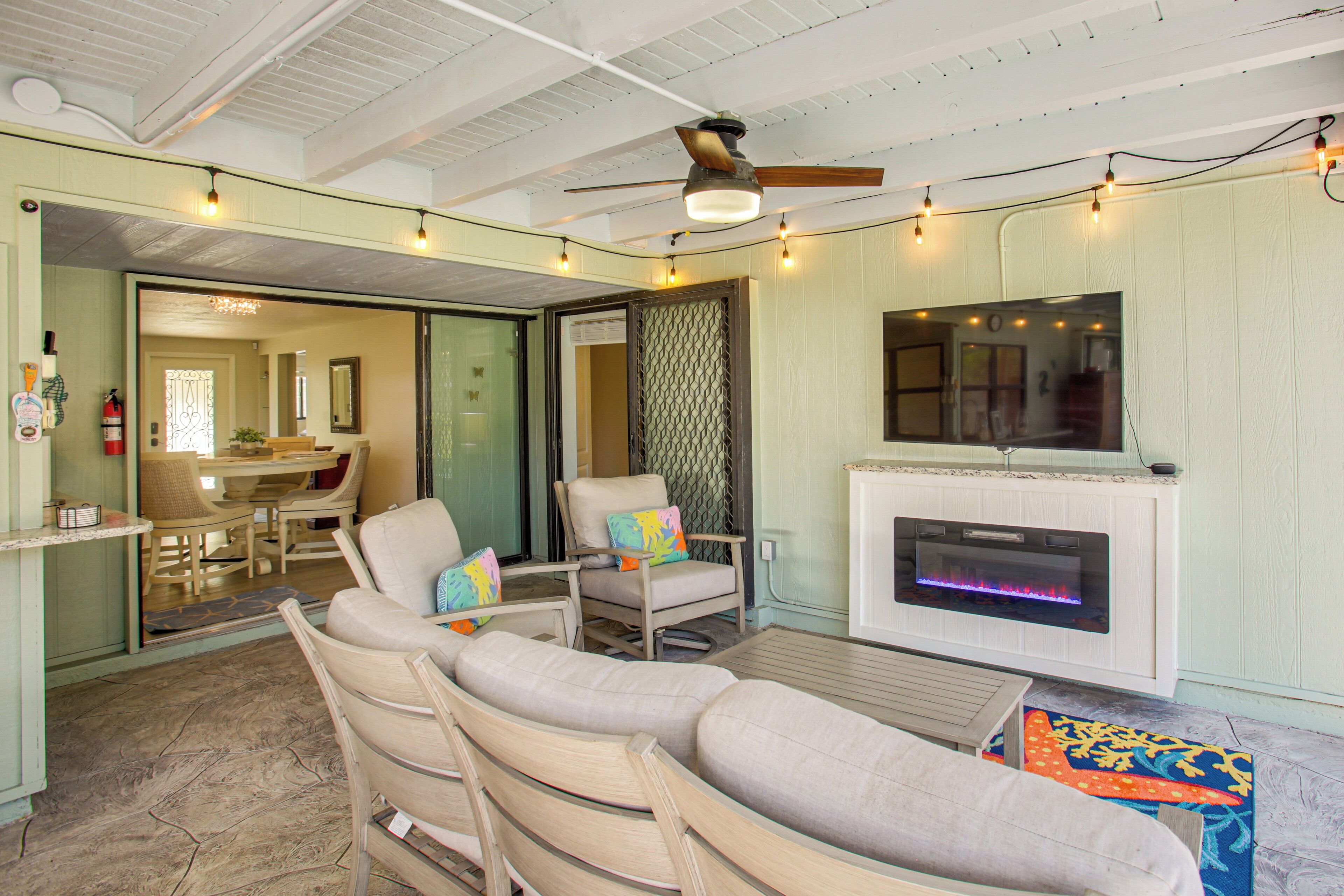 A living room with a fireplace, ceiling fan, and string lights.