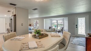 A modern kitchen with a central island, dining chairs, and a refrigerator. - Port Charlotte Home w/ Heated Pool & Yard! (Port Charlotte)