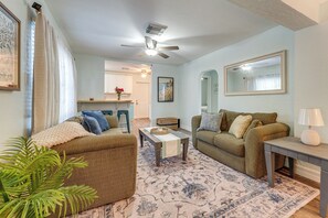A living room with a ceiling fan, a coffee table, two sofas, a lamp, and a large mirror. - 5 Mi to St Pete Beach! Snowbird Home w/ Large Yard (St. Petersburg)