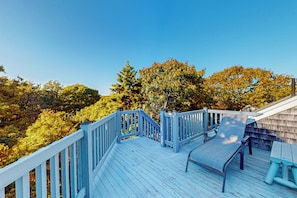 Um deck de madeira com guarda-corpo azul, um banco e uma mesa de piquenique.