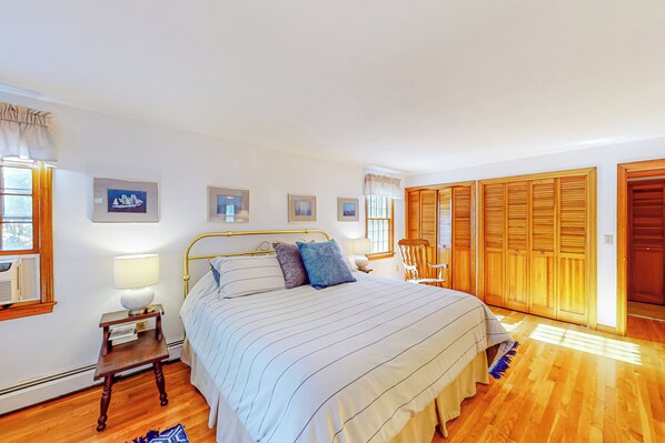 Une chambre avec un grand lit, un plancher en bois et une armoire aux portes coulissantes.
