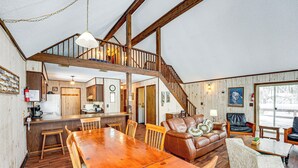 Un vaste espace de vie comprenant une table à manger en bois, un canapé en cuir et un escalier menant à un niveau supérieur.