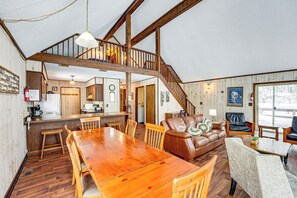 Un vaste espace de vie comprenant une table à manger en bois, un canapé en cuir et un escalier menant à un niveau supérieur.
