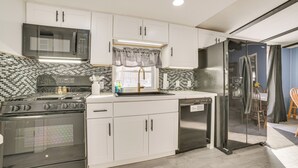 Una cocina moderna con armarios blancos, un refrigerador de acero inoxidable, un microondas y una estufa.
