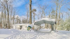 Un sendero cubierto de nieve que lleva a una estructura con un banco y un pequeño edificio.