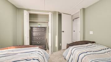 A bedroom with two beds, a dresser, and a closet.