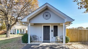 Une petite maison de plain-pied, dotée d’un porche à l’avant, d’une fenêtre circulaire décorative et d’une porte d’entrée sombre.