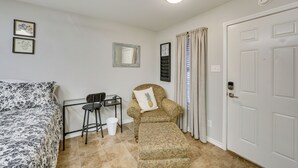 Une chambre à coucher avec un lit, une chaise, une petite table, un miroir et une porte.