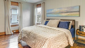 A bedroom with a large bed, wooden flooring, a ceiling fan, and a painting on the wall. - Walk to Marshall University: Home w/ Private Yard! (Huntington)