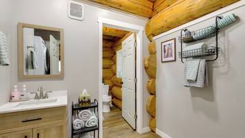 Une salle de bain avec un plafond en bois, un lavabo avec un miroir, des serviettes sur un porte-serviettes et des toilettes.