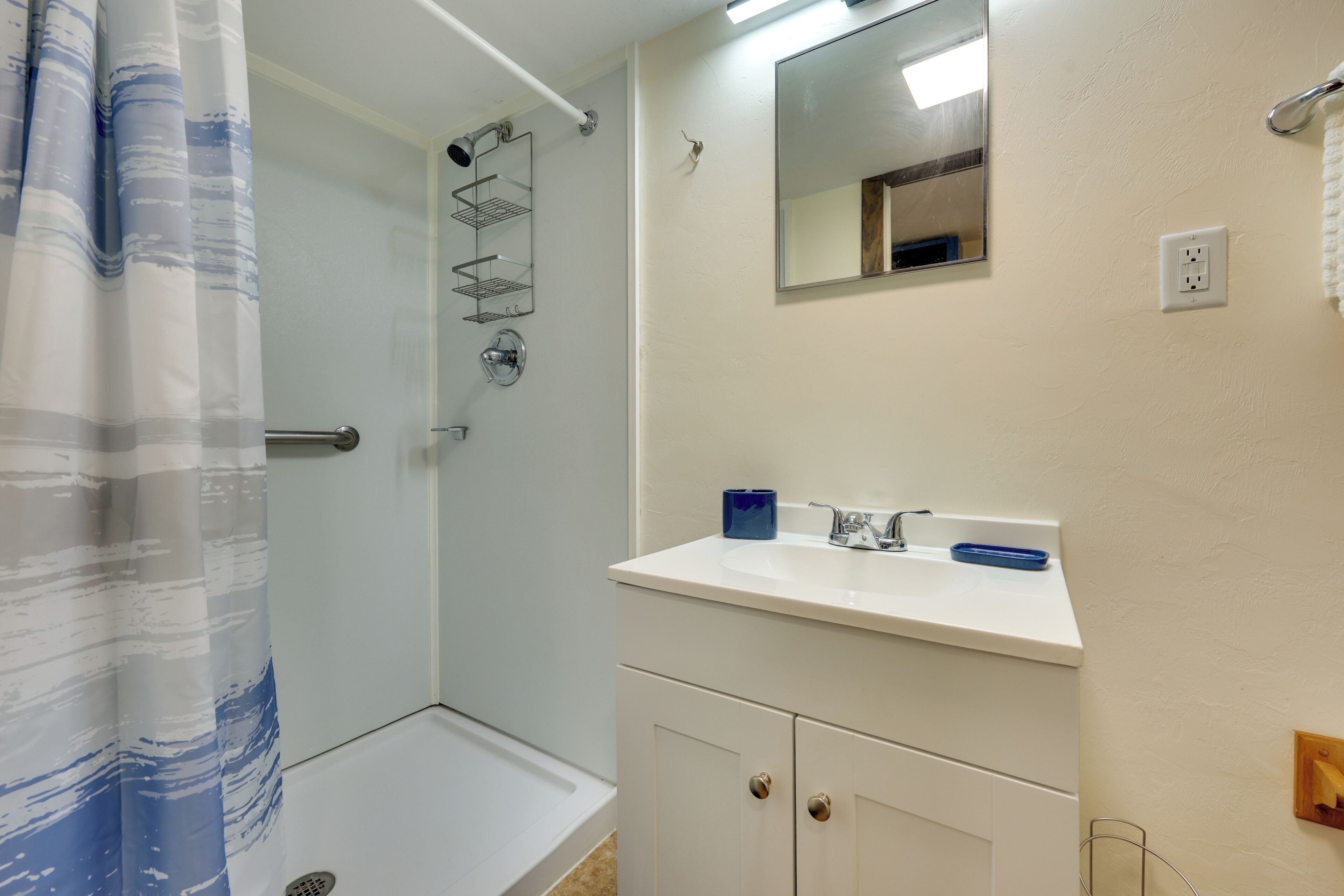 A bathroom with a shower, a sink, and a mirror.
