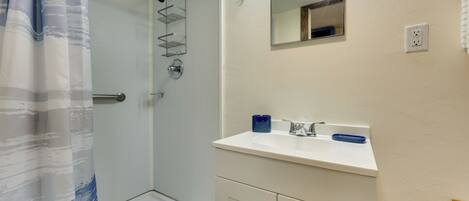 A bathroom with a shower, a sink, and a mirror.