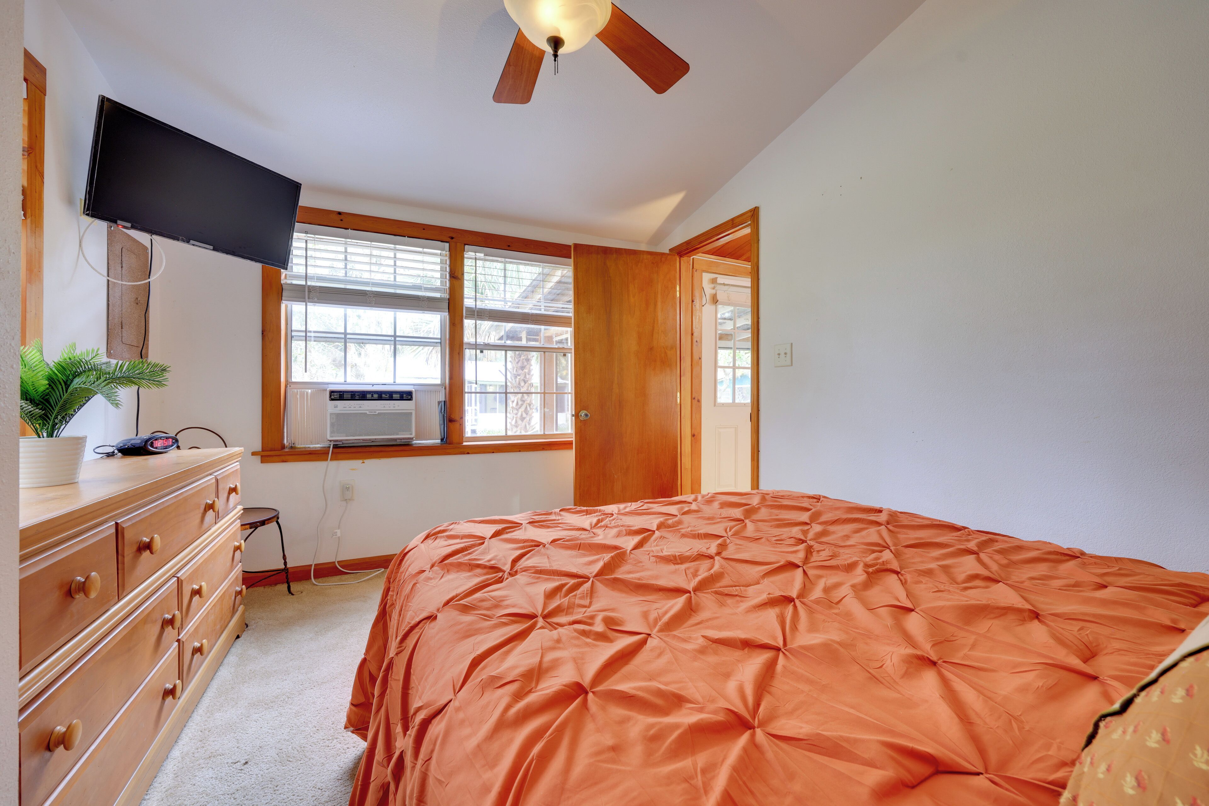 A bedroom with a bed, a dresser, a television, and a ceiling fan.