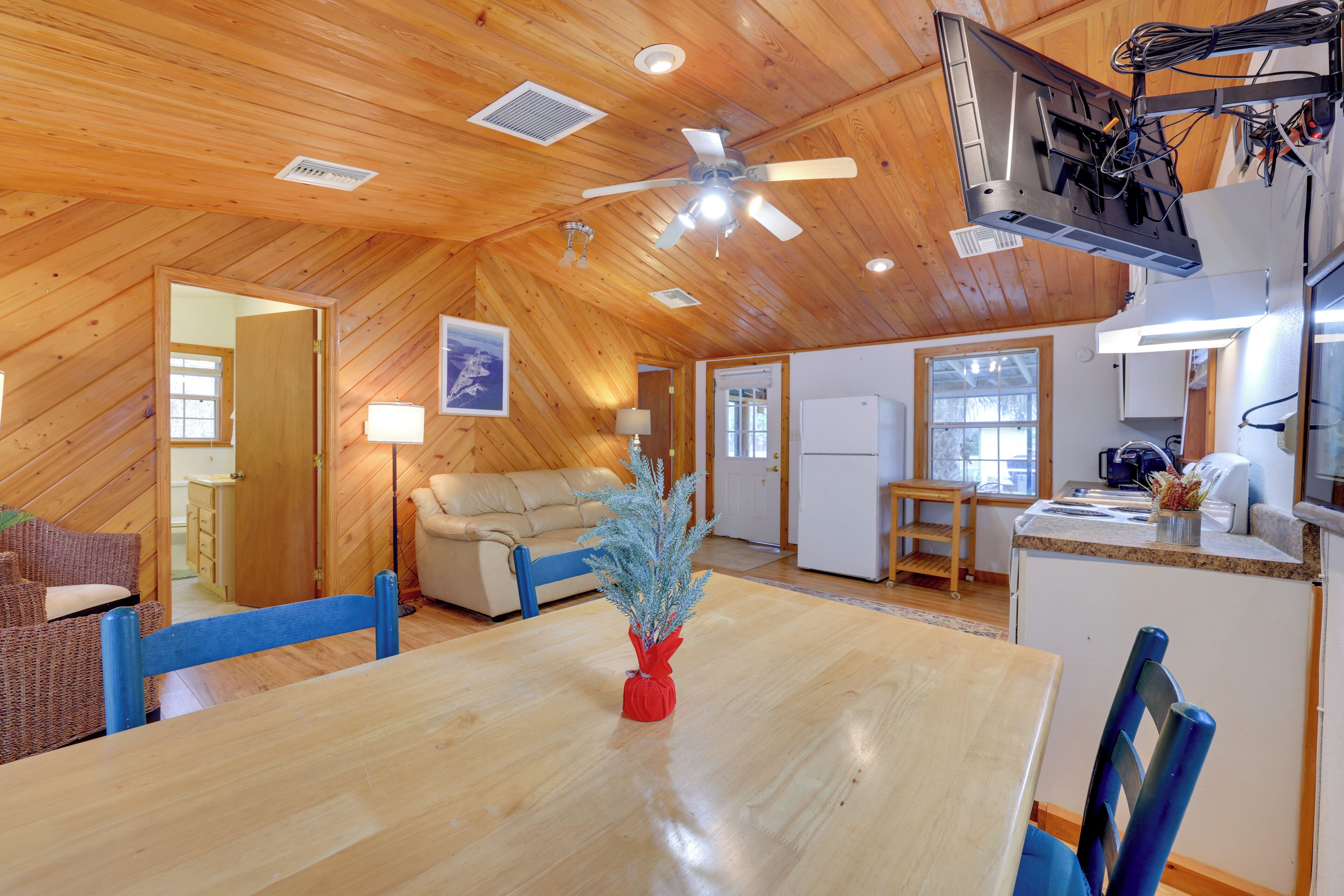 Una habitación amplia con techo de madera, una mesa de comedor, sillas, un sofá y una zona de cocina.