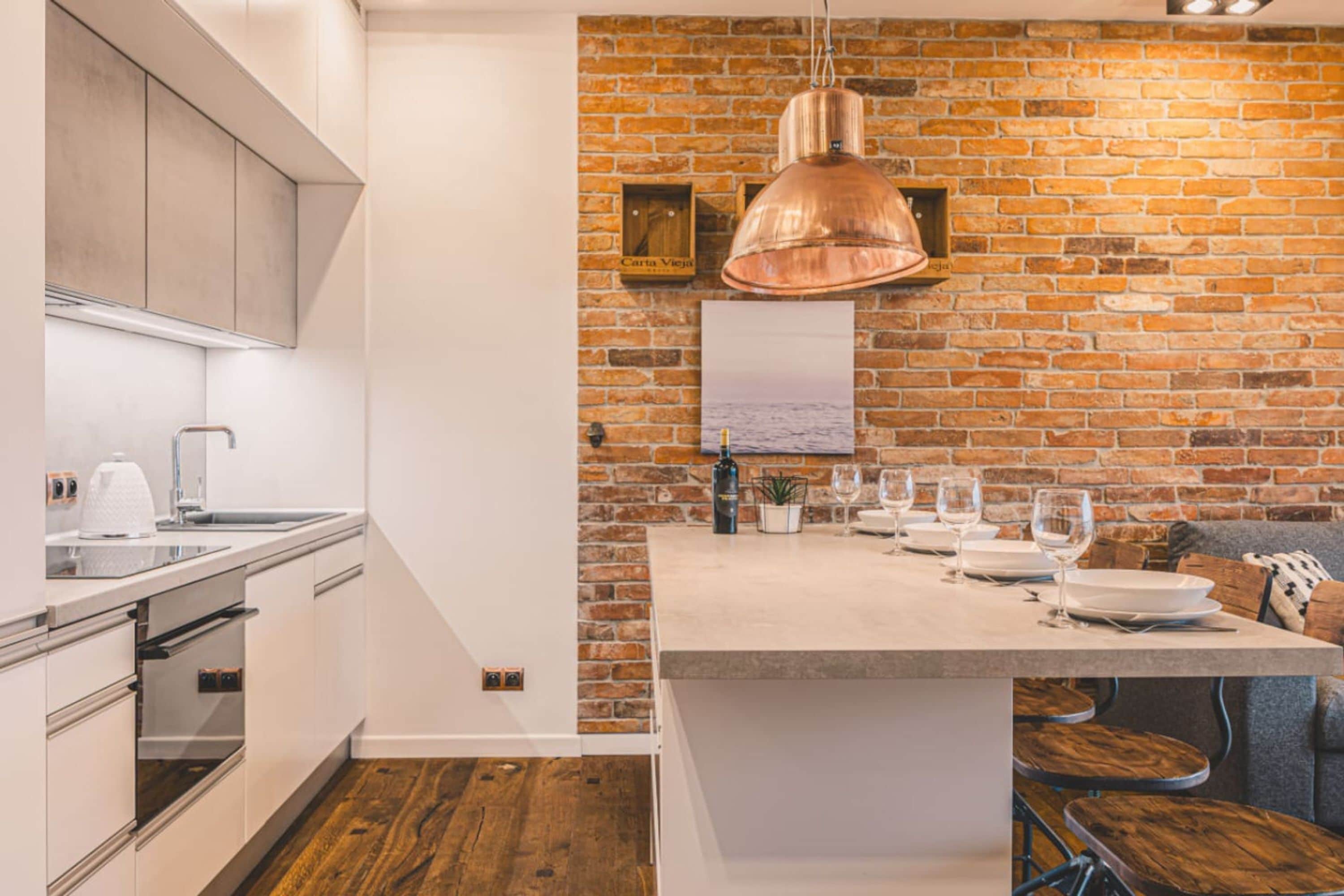 Una cocina moderna con pared de ladrillo, electrodomésticos de acero inoxidable y una zona de comedor de madera.
