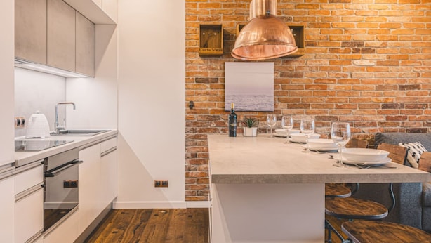 A modern kitchen with a brick wall, stainless steel appliances, and a wooden dining area. - Ladrillo - Luksusowy Loft z Widokiem na Miasto (Bydgoszcz)