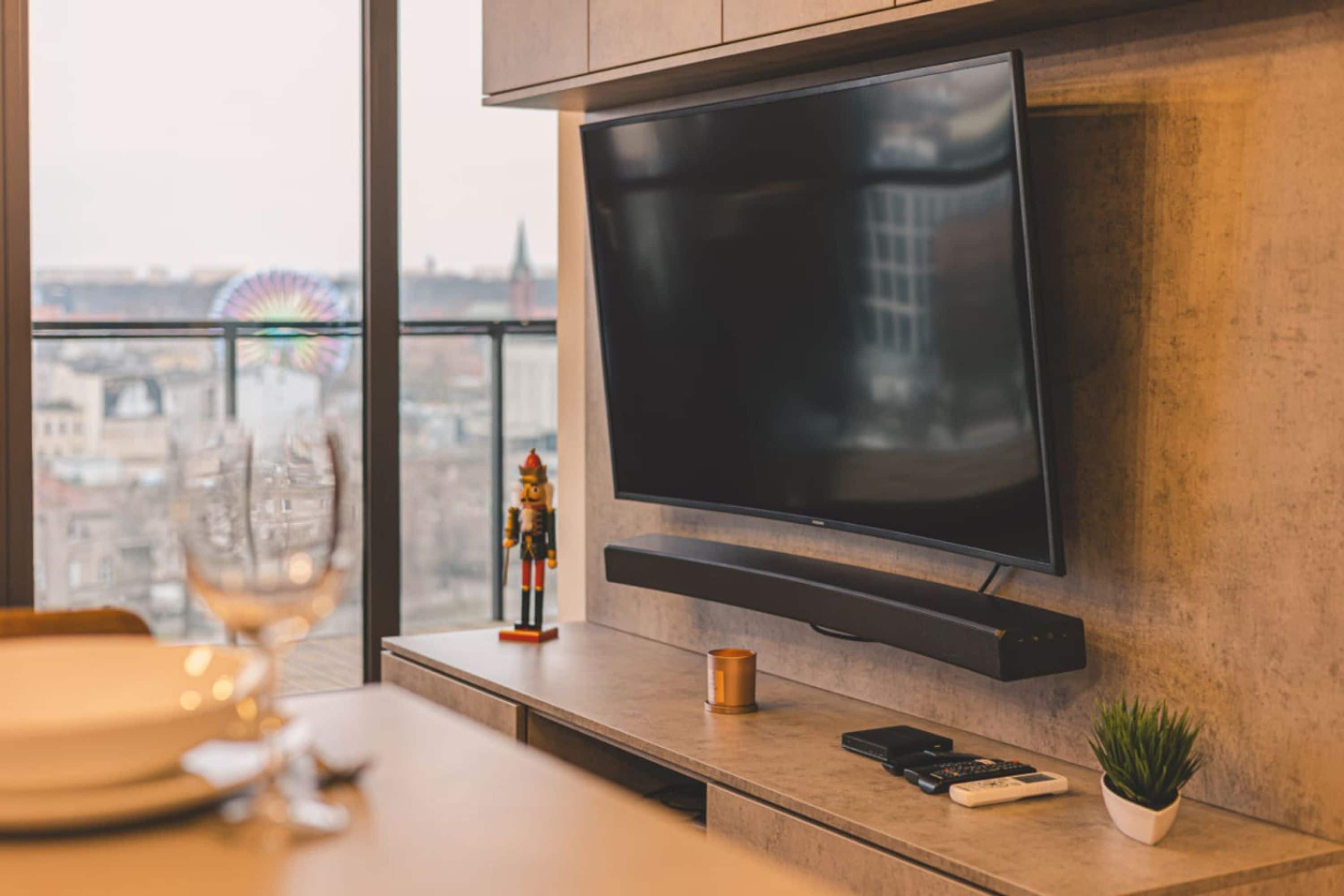 Una sala de estar moderna con un televisor de pantalla plana montado en la pared, una mesita con una planta, un control remoto y una figurita decorativa de soldado de hojalata.