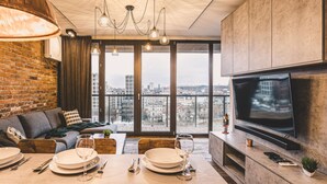Un salon moderne doté d’un grand téléviseur, d’un coin repas et offrant une vue sur la ville.