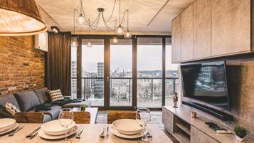 A modern living room with a large TV, dining area, and a view of the city.