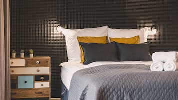 Una cama bien hecha con cubrecolchón acolchado, una mesita de noche de madera con cajones y una pared con textura.