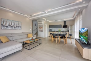 A modern living room with a sofa, coffee table, and a painting of sailboats. - Sea View Villa Maria With Pool (Medulin)