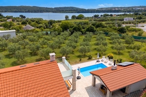 A residential property with a swimming pool, olive trees, and a view of a lake. - Sea View Villa Maria With Pool (Medulin)