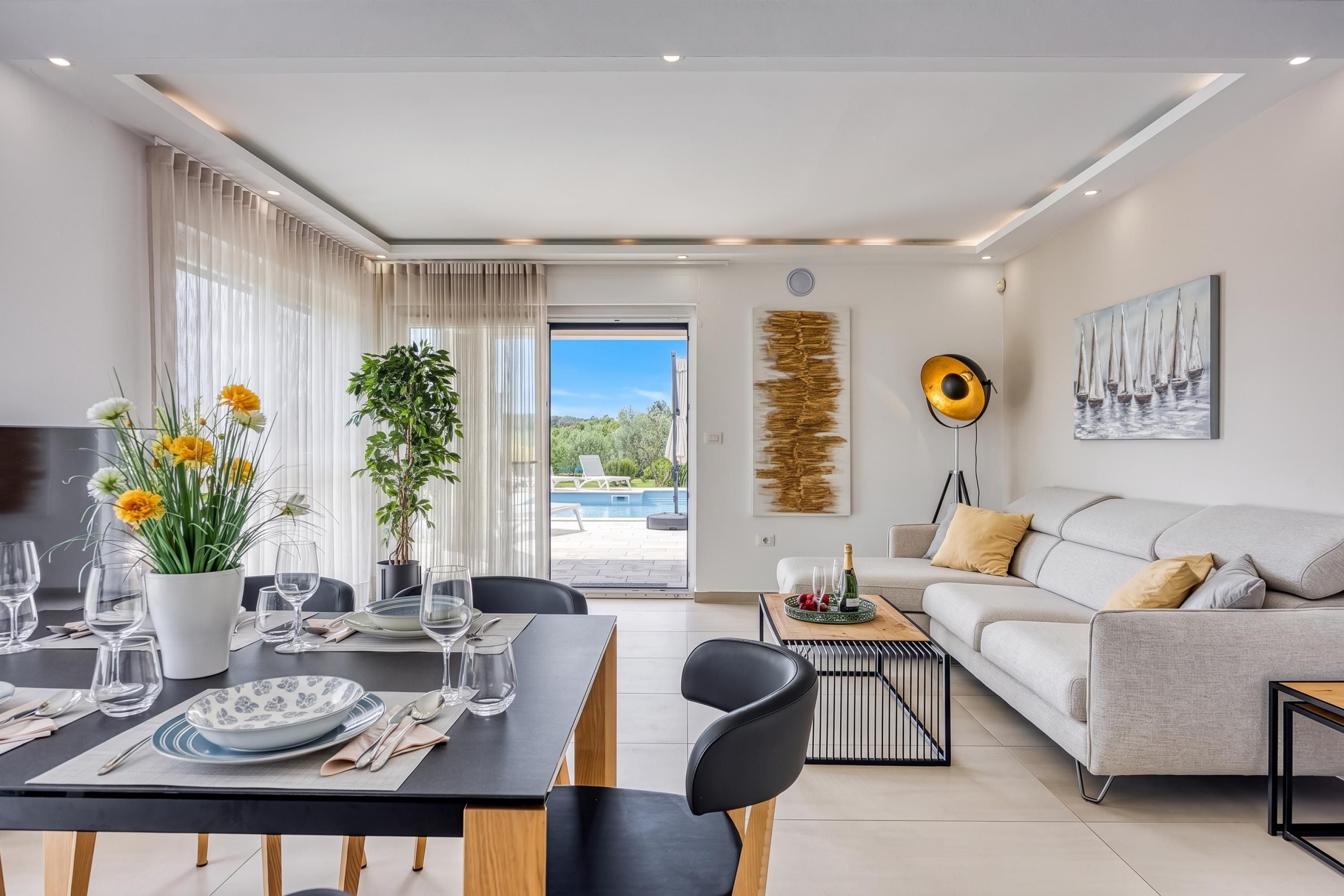Un salon moderne comprenant un coin repas, un canapé et donnant sur une piscine.