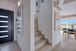 A modern interior with a staircase, a dining area with a table and chairs, and a large window with a view. - Sea View Villa Maria With Pool (Medulin)