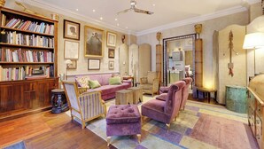 A well-furnished living room with a bookshelf, a sofa, armchairs, a coffee table, and a mirror. - Historic Elegance in the Heart of Marais - 6p/2br (Paris)
