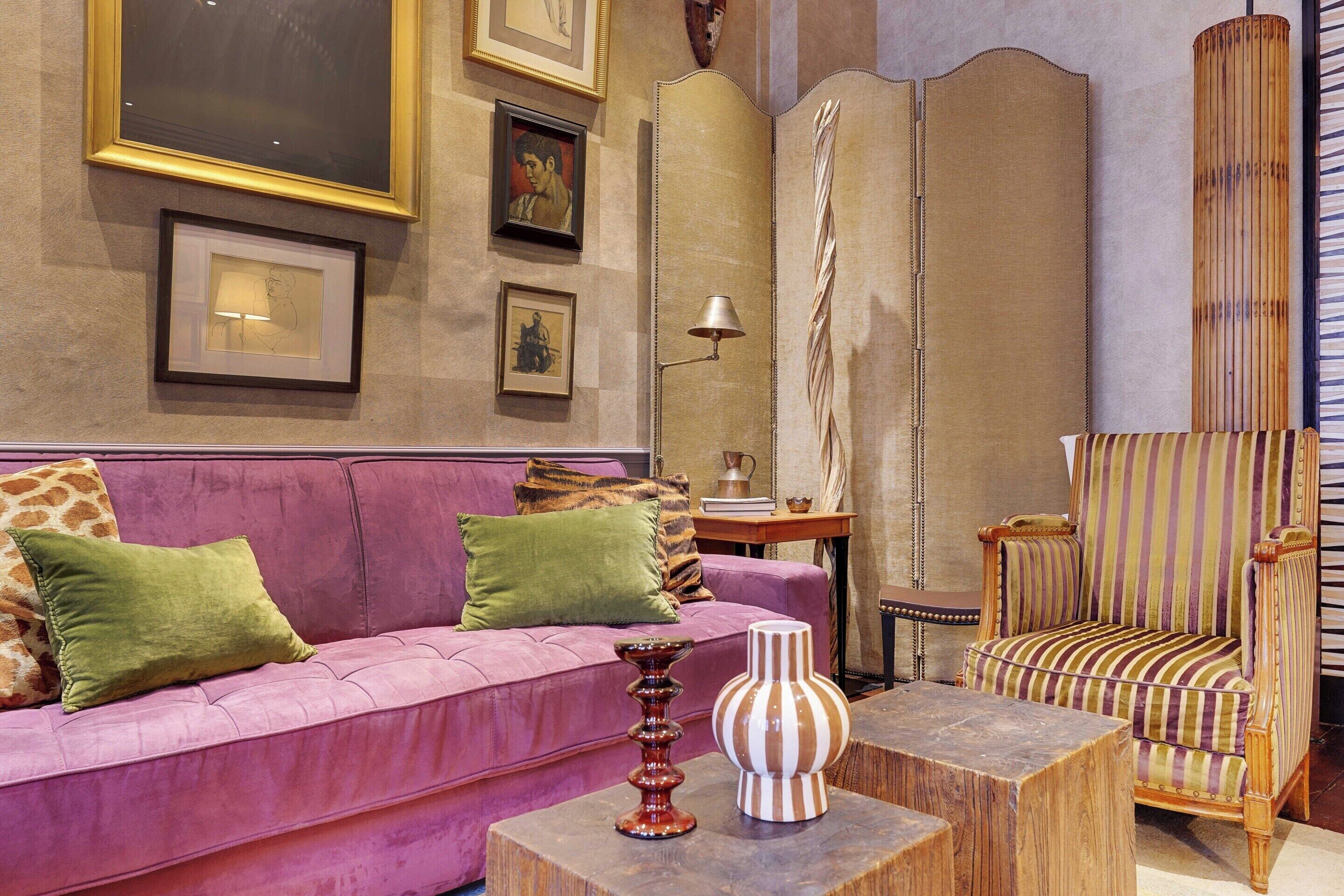 A room with a purple sofa, a striped armchair, a wooden coffee table, and a decorative vase.