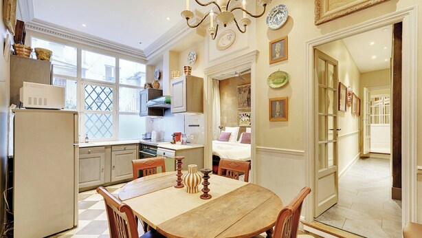 A kitchen with a dining table, chairs, a refrigerator, and a chandelier. - Historic Elegance in the Heart of Marais - 6p/2br (Paris)