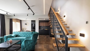 A modern living room with a teal sofa, a coffee table, and a staircase with wooden steps. - Villa Betelgeuse Supernova (Novi Vinodolski)